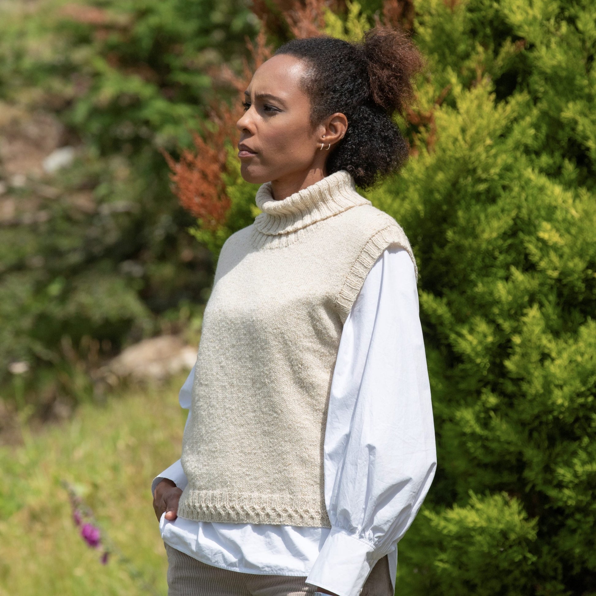 Women standing in the countryside, in a cream roll neck sweater