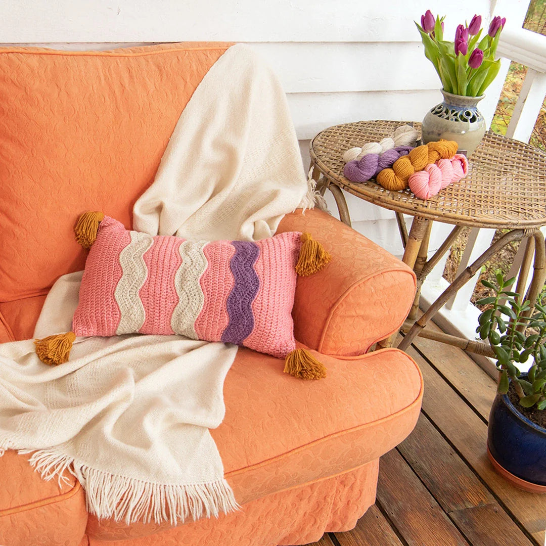 Drifting Away Pillow is a contemporary crochet pillow pattern featuring fun squiggle details and four chunky tassels.